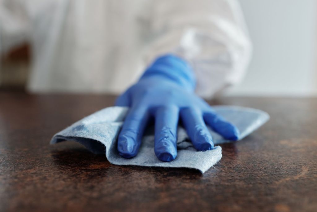 hand in blue glove wiping surface